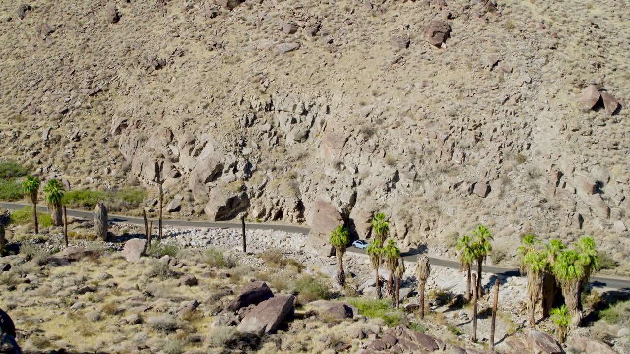 Aerial view of rugged Palm Springs mountain terrain, showcasing dramatic ridges, rocky slopes, and desert textures under a clear blue sky