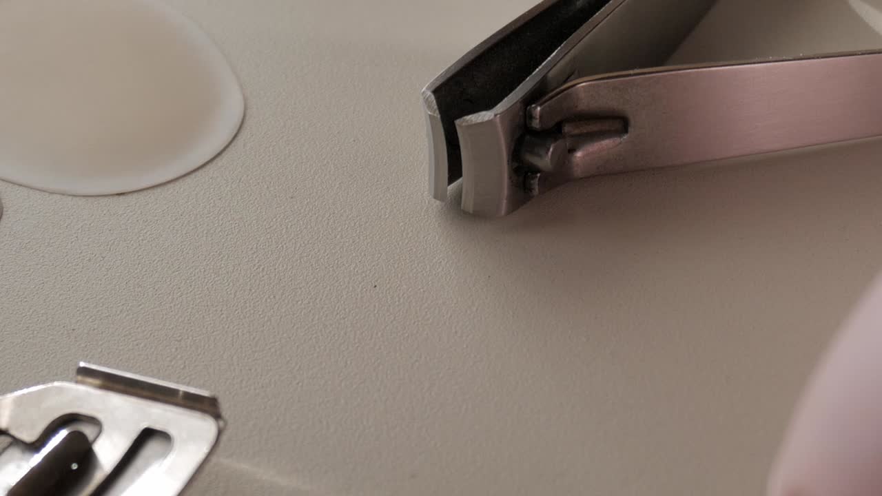 Close-up of manicure tools and equipment on a clean surface with focus on clipper