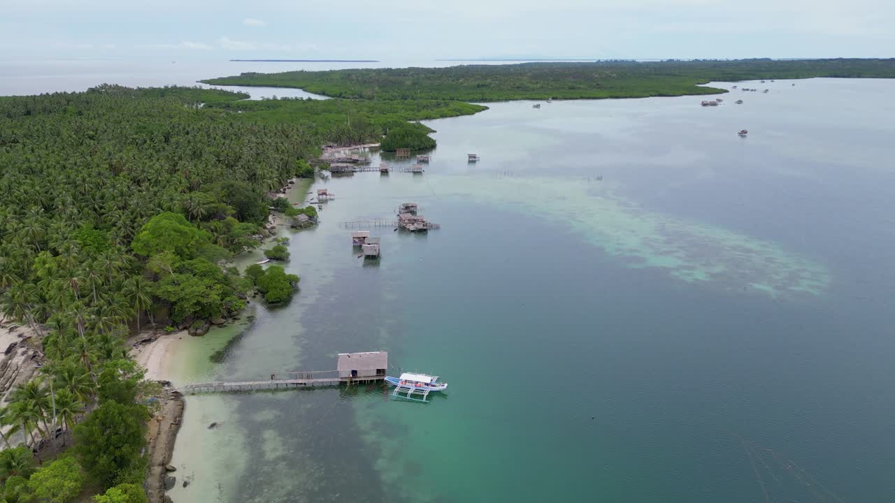 drone desciende sobre la isla de balabac con palmeras, canoa banca y casa en el agua