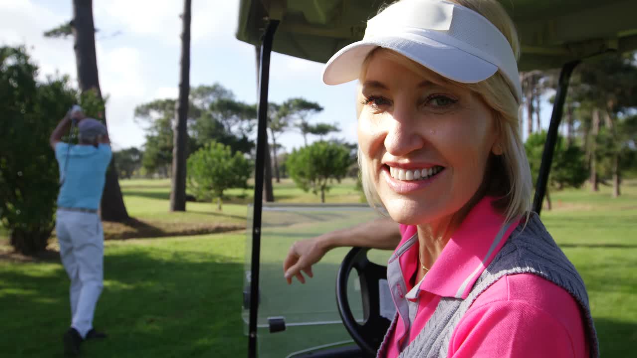 Golfista donna felice seduta su un golf cart