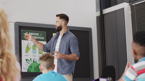 maestro masculino diverso y escolares felices en el escritorio en el aula de la escuela