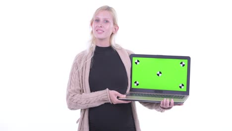 portrait of beautiful pregnant young blonde woman smiling and showing laptop computer with green screen copy space isolated against white background