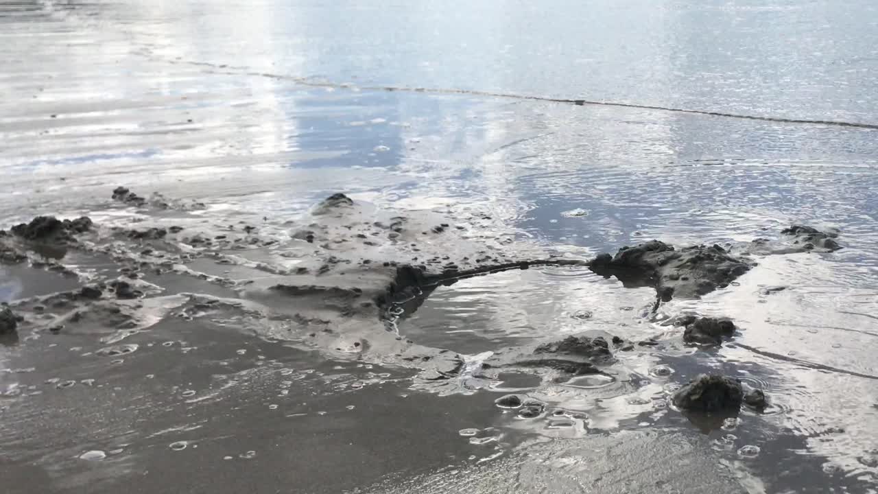 흐린 반사 해변 위로 모래 구멍으로 흐르는 바닷물 가까이
