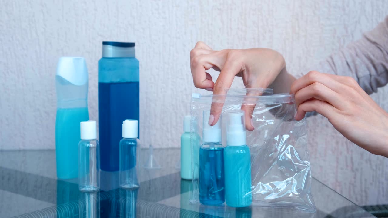 여성의 손은 시프 플라스틱 가방에 병과 항아리를 가진 화장품의 도로 세트를 넣습니다. 근접 항아리.