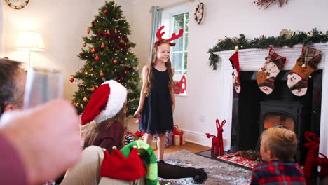 niña joven actuando como mímica como familia de varias generaciones jugando al juego de charadas navideñas en casa juntos