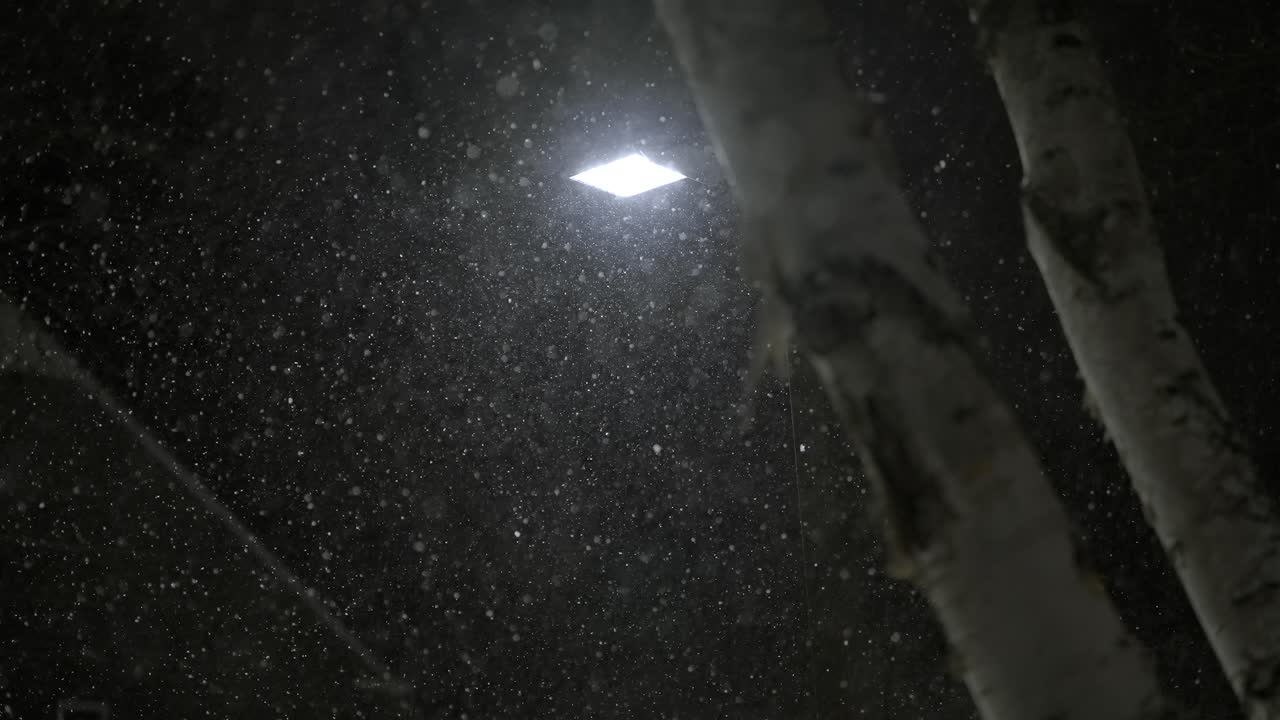 Slow motion snowfall at night, evening, street lamp, lantern is shining in the darkness, winter, copy space
