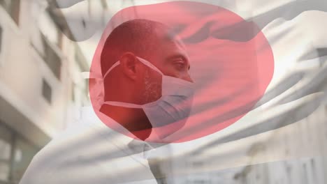 Animation-Der-Flagge-Japans,-Die-Während-Der-Covid-19-Pandemie-über-Einem-Mann-Mit-Gesichtsmaske-Winkt