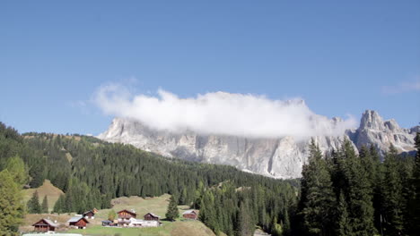 montagna dolomitica con lasso di tempo di nuvole con edifici rustici nelle vicinanze