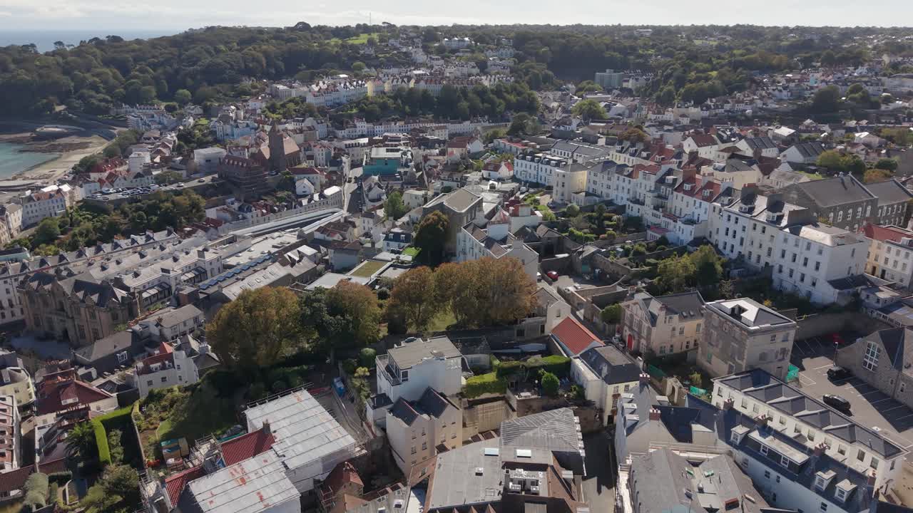Overhead flight over central St Peter Port Guernsey flying south on bright sunny day over homes,offices and main commercial area