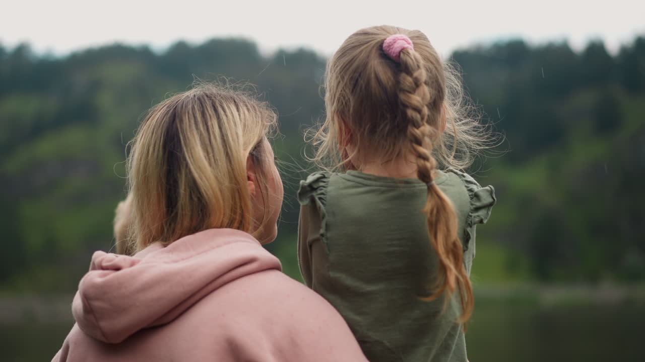 여자가 작은 아이들을 안아서 언덕에 대항하는 딸과 이야기합니다.