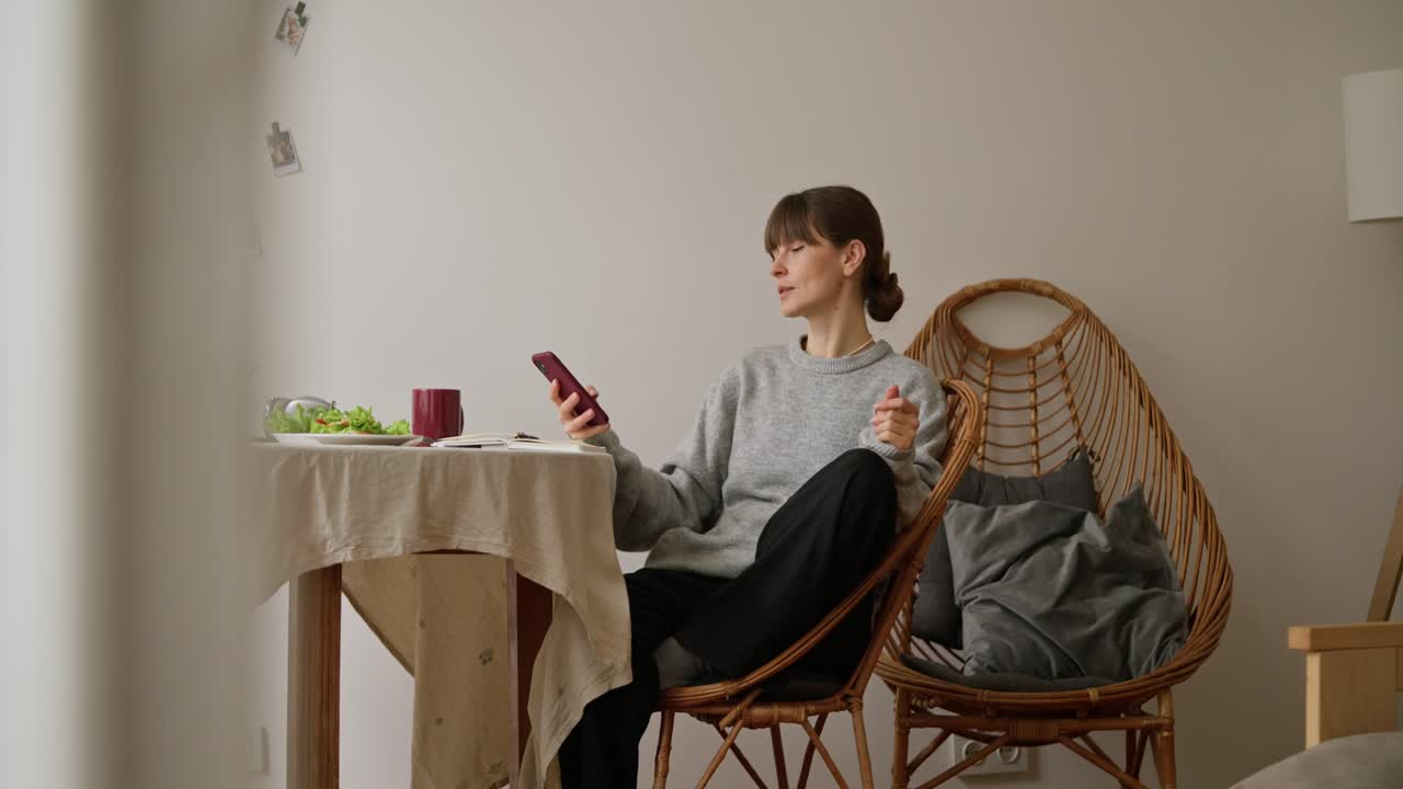 Woman using phone at dining table in cozy home