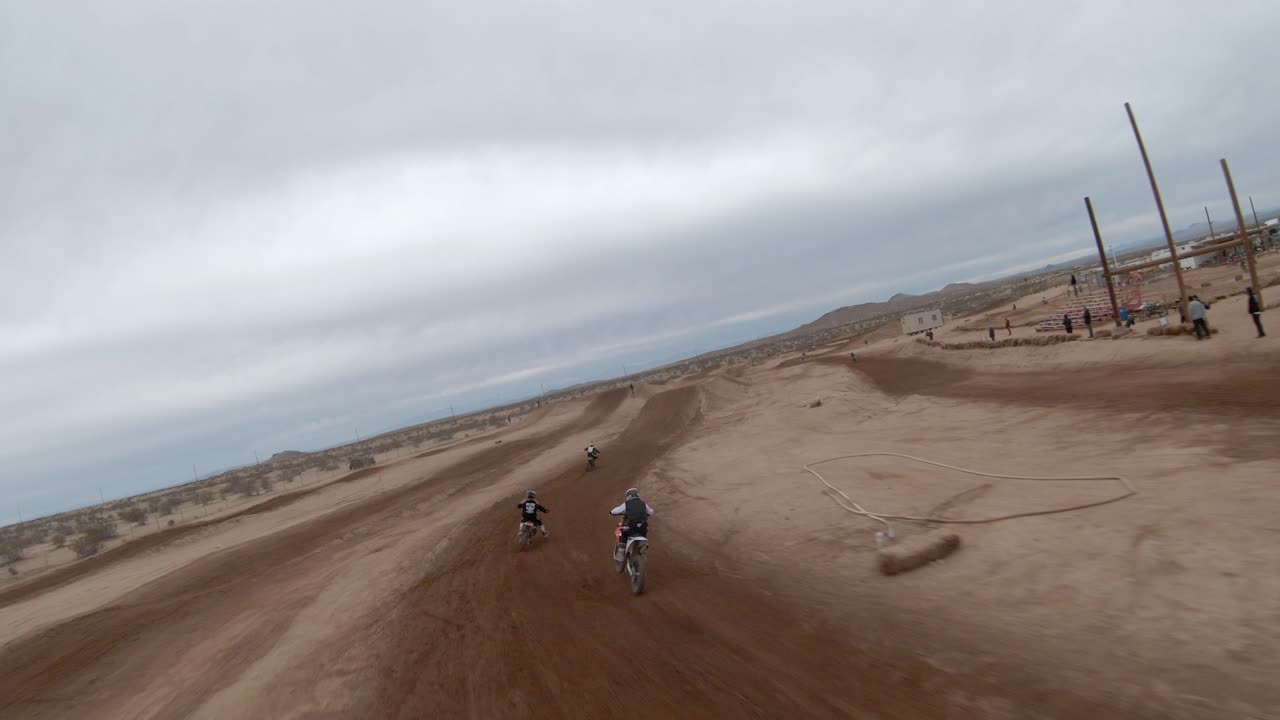 고속 드론을 사용하여 점프 위로 날아가는 모하비 사막의 경마장에서 오토바이를 추적합니다.