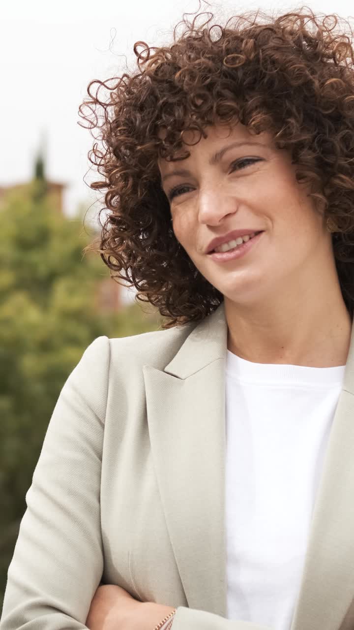 Confident businesswoman smiling with arms crossed in a professional setting. Vertical