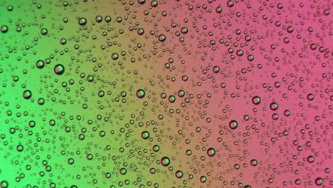 gotas de agua aparecen en la superficie del vidrio en verde y rosa