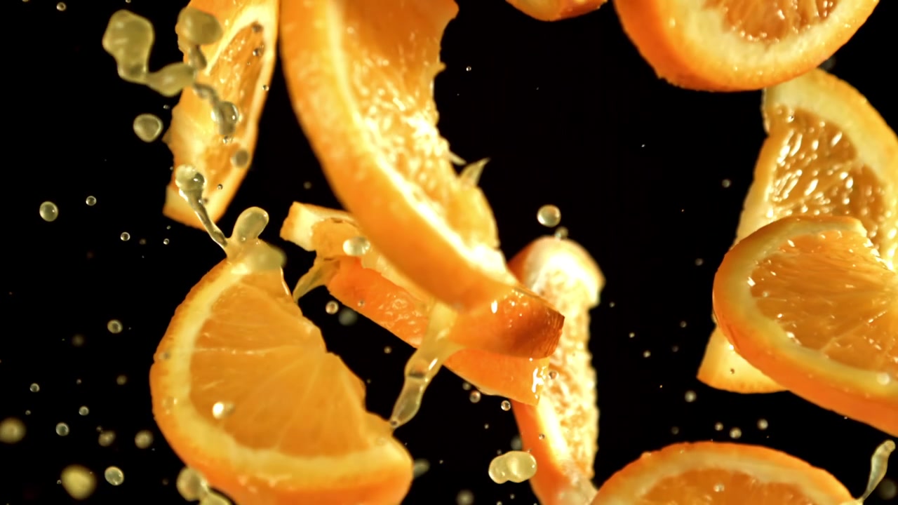 Fette d'arancia fresche e succo che schizzano in super slow motion.