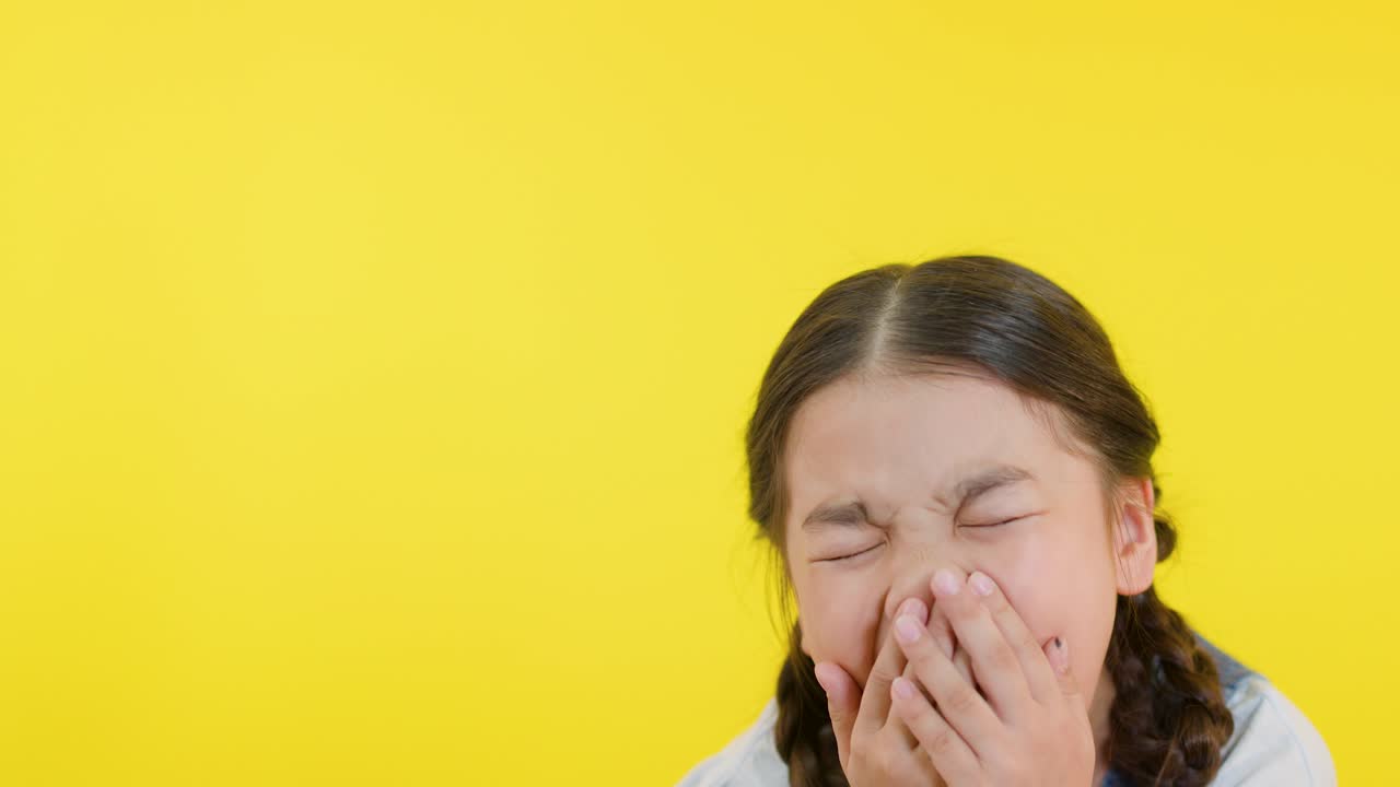 Girl with braids laughs, covers mouth, and smiles in bright, evenly lit studio setting