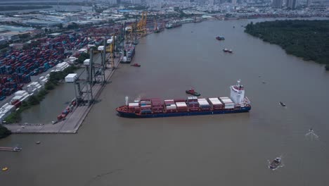 hyperlapse of a large container ship being turned around by tug boats and leaving the port on a sunny day