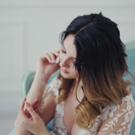 attractive young lady sitting on a sofa and prides herself in the room. beautiful bride in wedding dress dreaming of marriage while waiting for groom.