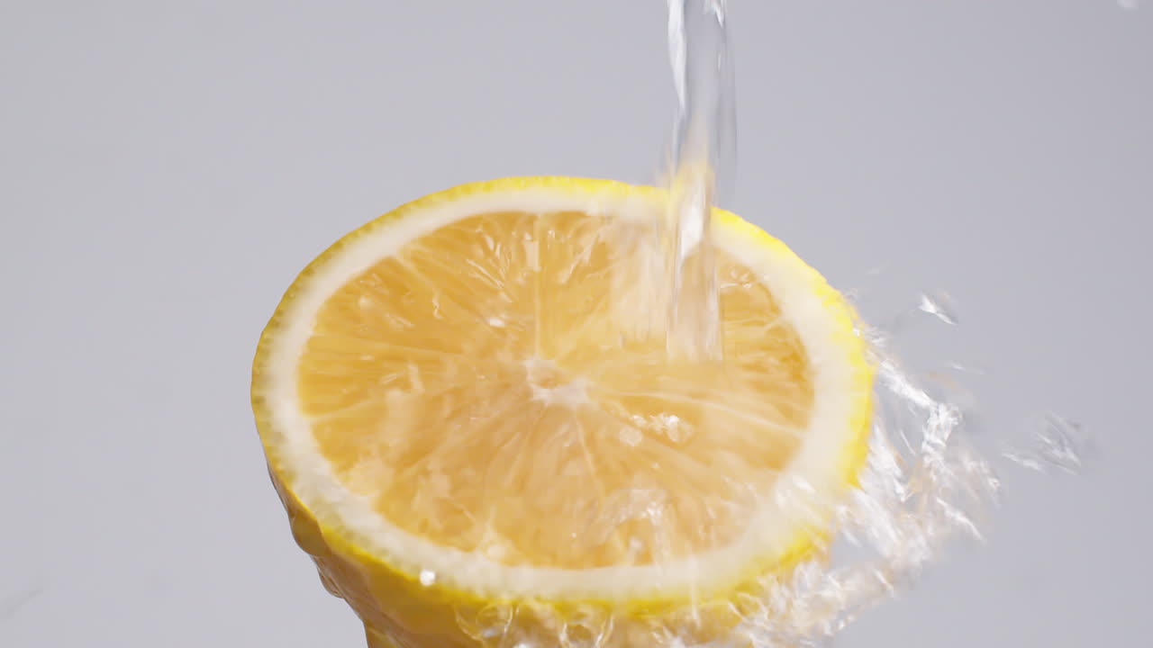 slow motion makro skud af flydende vand fra citron skive på hvid baggrund