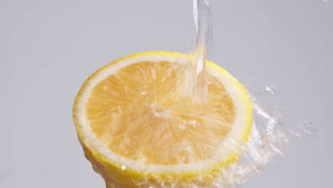 Slow-Motion-Macro-Shot-of-Flowing-Water-from-Lemon-Slice-on-white-Background