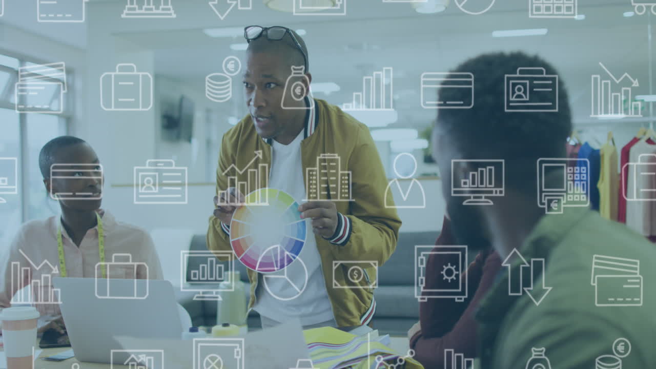 Animation of multiple icons over diverse man showing color swatch to coworkers in meeting at office