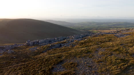 a 4k aerial drone shot rising over mountain landscape with fields background during sunset in brecon beacons, wales