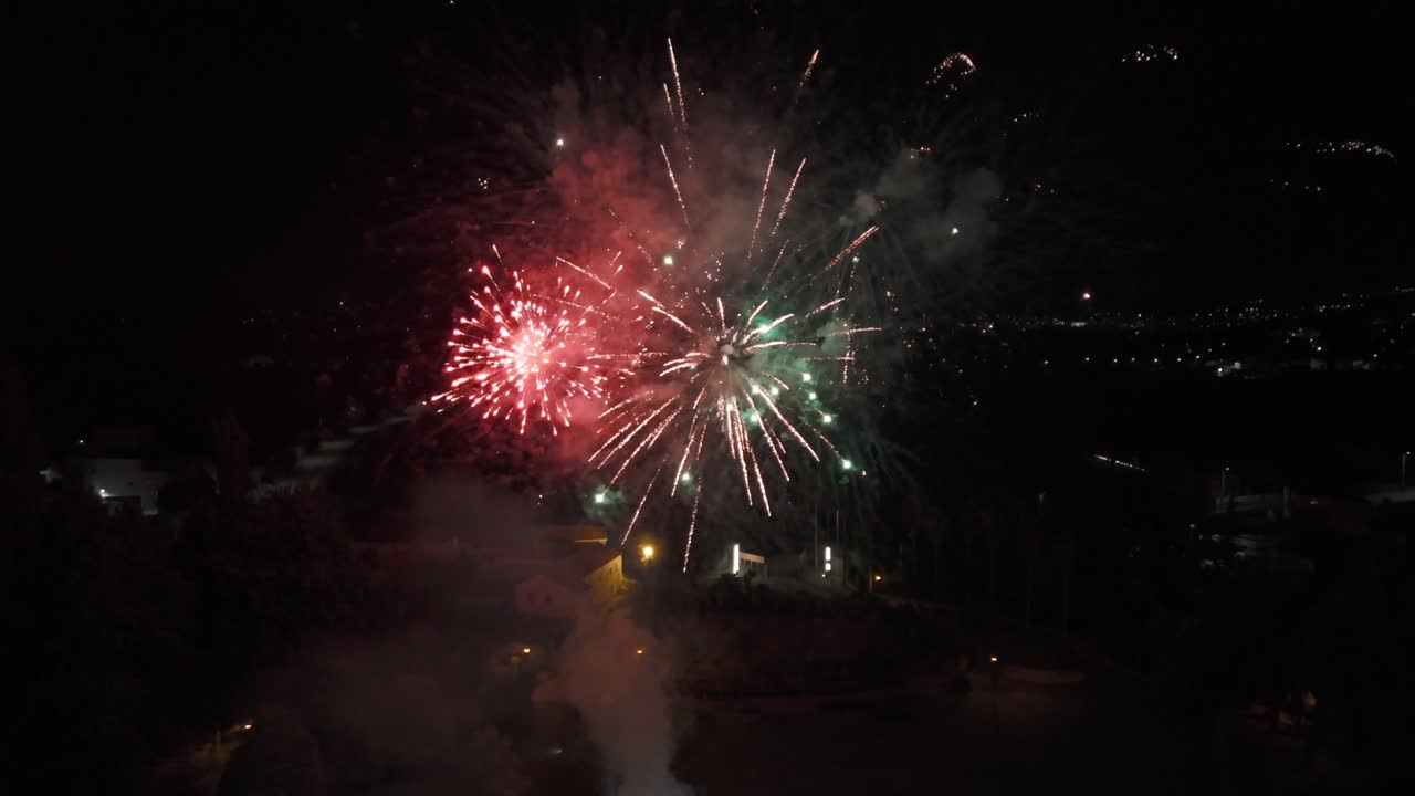 Fireworks illuminating the night sky with vibrant bursts of light over a city