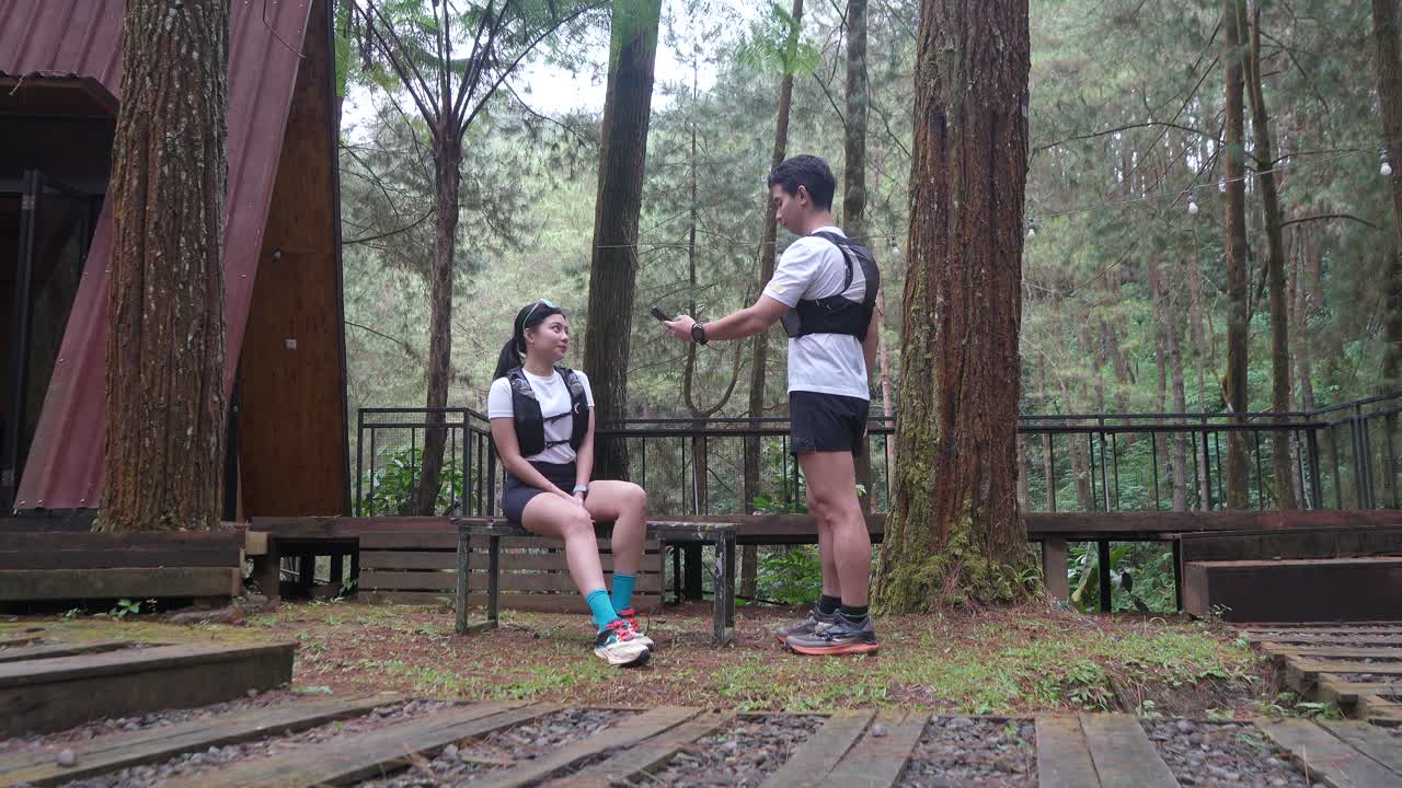 Asian couple taking photo with smartphone during outdoor trail run in Indonesian forest