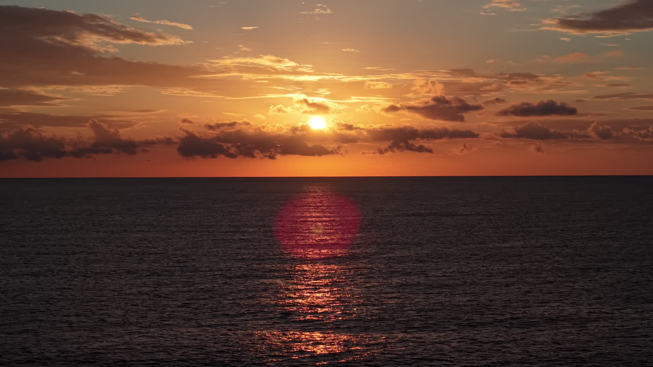 Tramonto vibrante arancione e giallo sull'oceano calmo