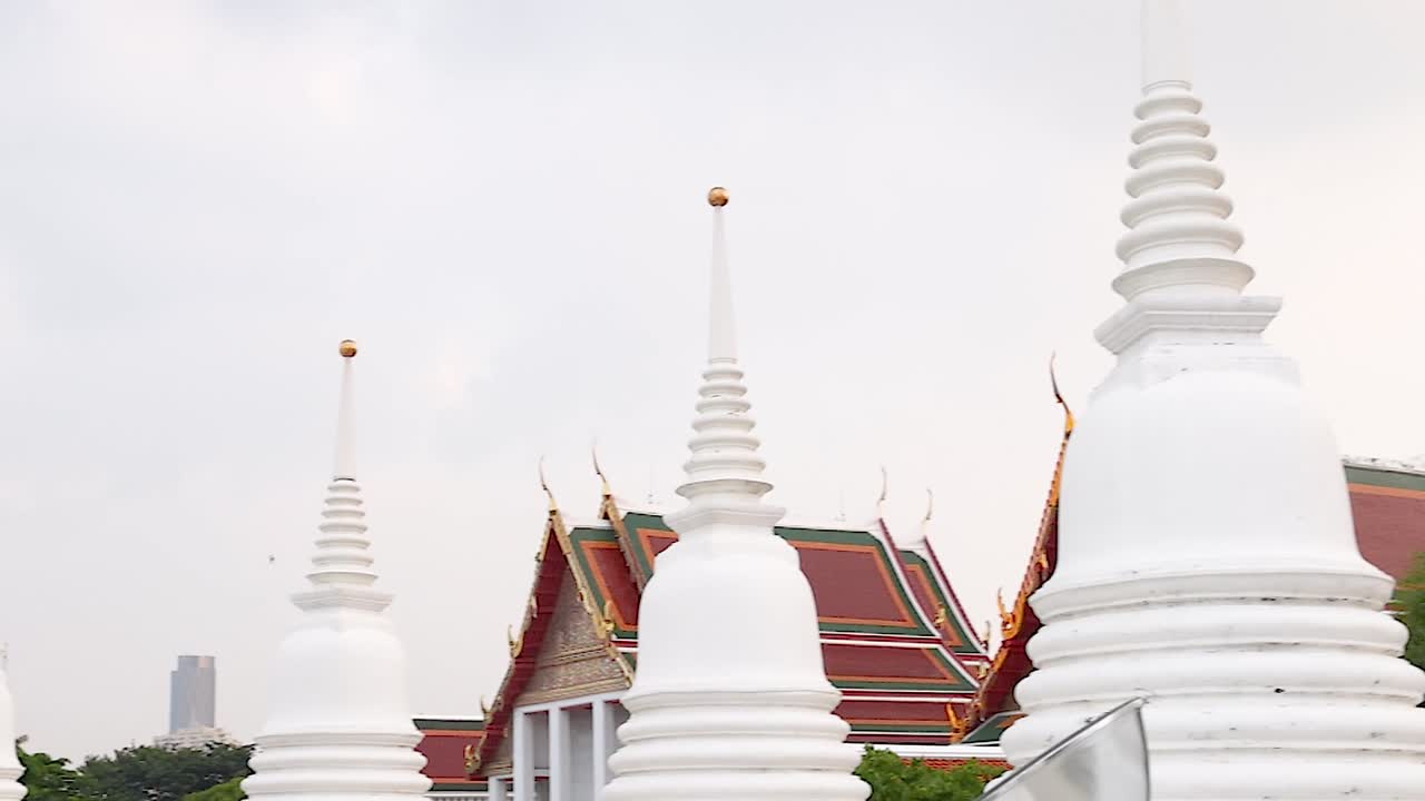 A close-up view of white stupas and traditional rooftops against a city backdrop.
