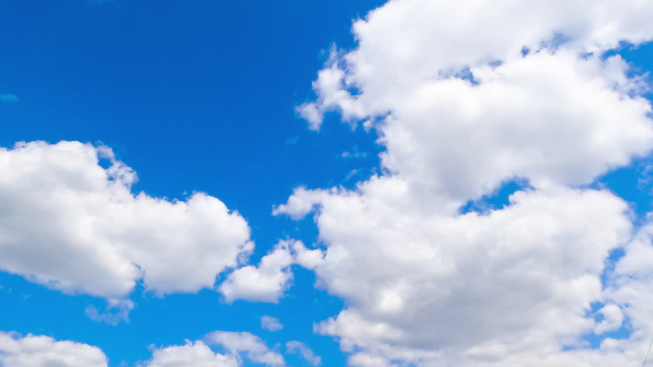 Beautiful azure summer sky with white clouds quickly changing shape. Low angle view timelapse.