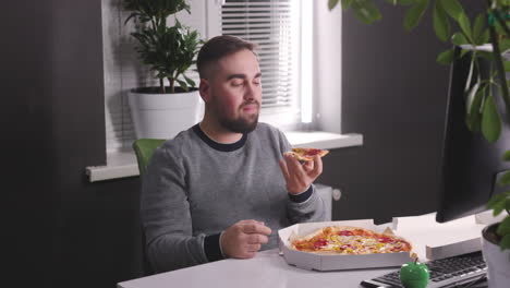 hungry man having a break and eating tasty pizza at office