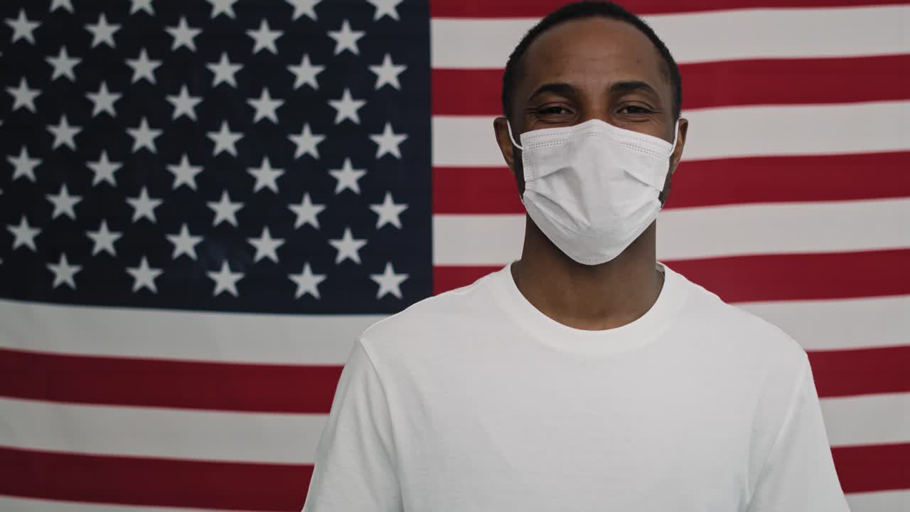 video de un hombre con una máscara en la bandera estadounidense