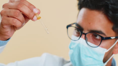 indian young doctor scientist man carefully drips liquid from the pipette doing research analysis