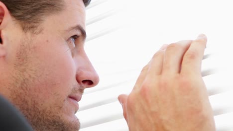 Businessman-peeking-through-roller-blind