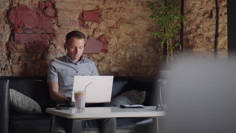 un hombre serio es un estudiante de negocios trabajando estudiando sentado en una mesa y escribiendo un mensaje en una computadora portátil. escribiendo texto en el teclado