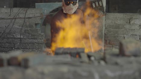 un herrero alimentando un incendio en un taller de forja de hierro.