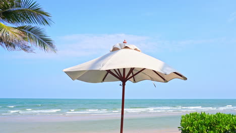 a topical breeze ripples along the edges of a canvas beach shade umbrella