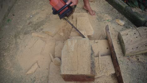 tallador de madera recortando la madera para la máscara de barong con una motosierra