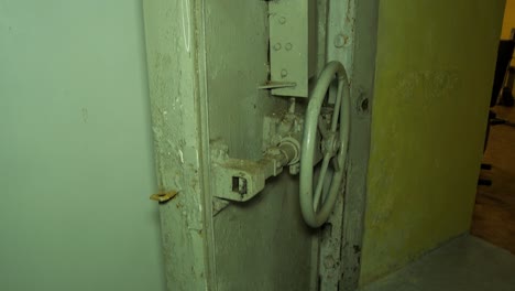 steel door inside the concrete bomb shelter to hide civil people, an underground apocalypse bunker built in old coastal fortification, medium handheld shot tilt down