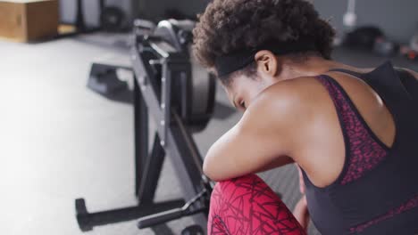 video de una mujer afroamericana cansada en una máquina de remo recuperándose después de hacer ejercicio en un gimnasio