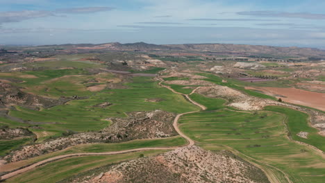 soleado hermoso aéreo sobre un camino y campos verdes alcaniz españa colinas rocosas