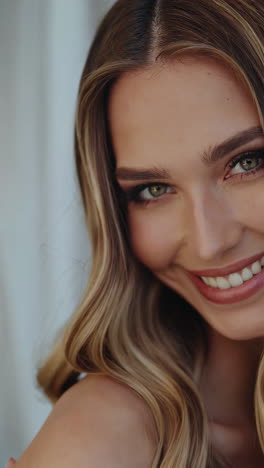 close-up portrait of a beautiful smiling woman with wavy blonde hair and green eyes