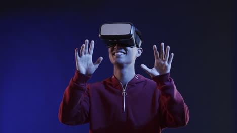 asian man using vr headset, touching virtual screen on blue background, slow motion