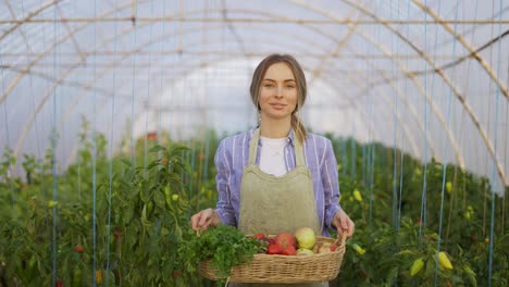 Mujer-Campesina-Feliz-Caminando-Con-Una-Canasta-Con-Verduras-Frescas-Cosechadas-En-El-Invernadero