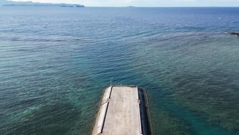 Bird's-eye-View-of-Cemented-Dock-facing-breathtaking,-clear-ocean-waters-and-coral-reefs-in-Catanduanes,-Philippines
