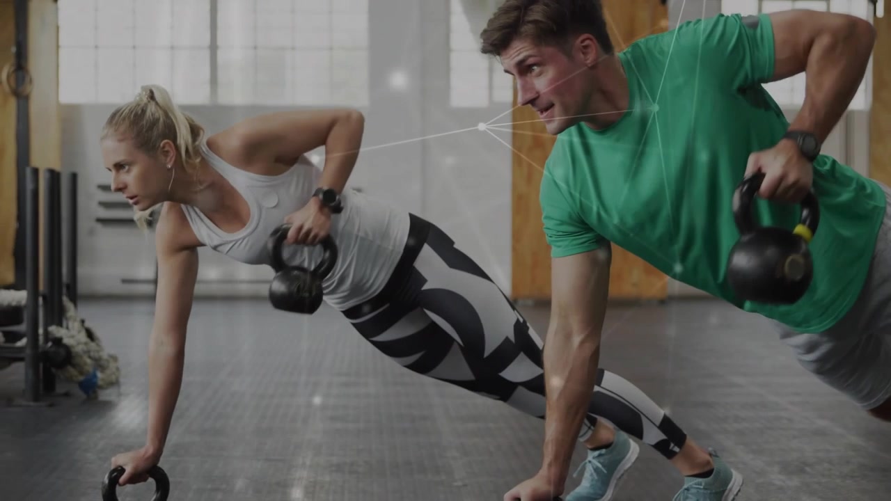 Homem e mulher fazendo prancha alta e depois mudando para remadas alternadas com kettlebell para fitness