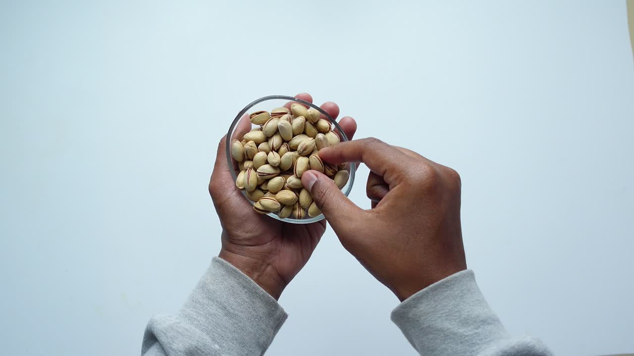 Mani che reggono una ciotola di vetro di pistacchi