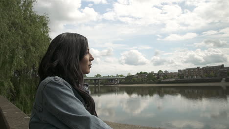 turista latina mirando el río támesis y el puente de putney en londres, sonriendo y pasándola muy bien