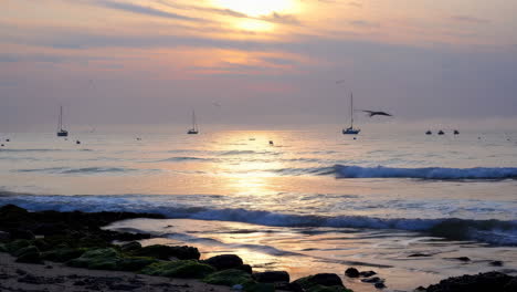 sunrise or sunset at the beach with sailboats